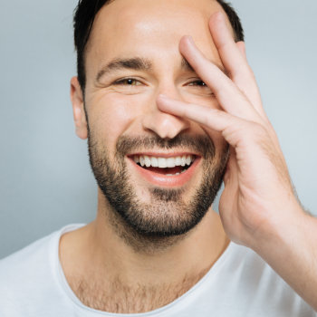 handsome young man covers laughing face