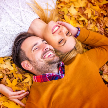 laughing couple lies on autumn leaves
