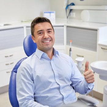 satisfied man shows thumbs up while sitting in the dentist chair