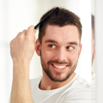 the man smiles and trims his hair