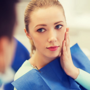 young woman sitting with toothache in the dental chair